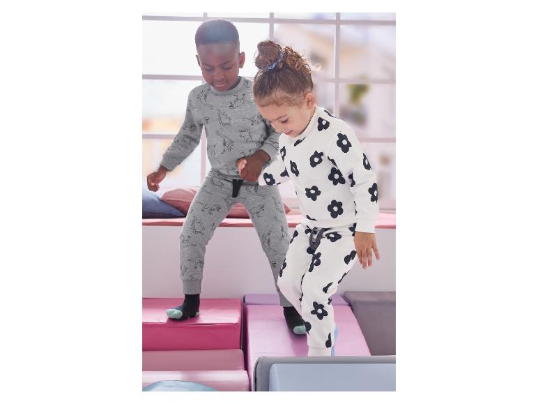 Dve deti v pyžamách s dinosaurami a kvetmi, hrajúce sa na mäkkých blokoch.