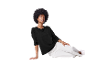 Modelka s veľkým afro účesom pózuje v čiernom svetri a bielych nohaviciach.