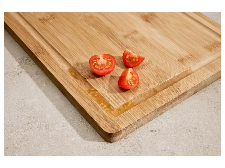 Bambusová doska na krájanie s nakrájanými cherry paradajkami a šťavou.