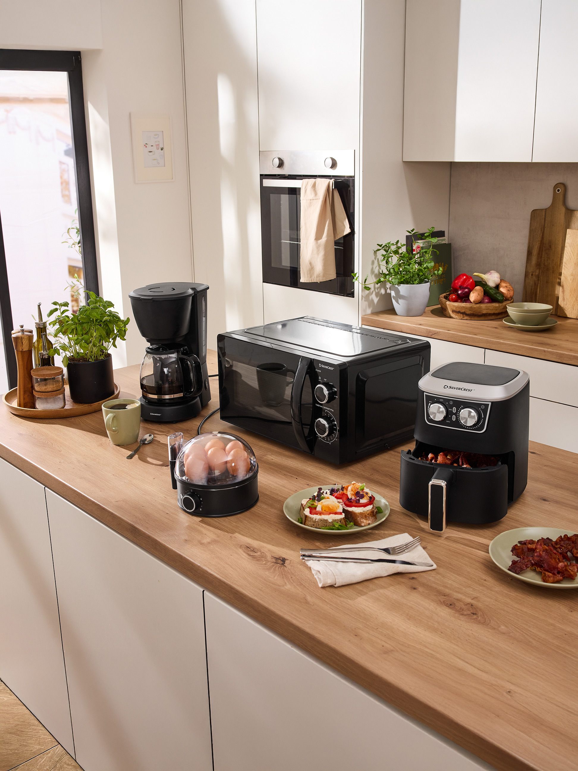 Kuchynská linka s mikrovlnnou rúrou SilverCrest, kávovarom, fritézou a raňajkovými spotrebičmi.