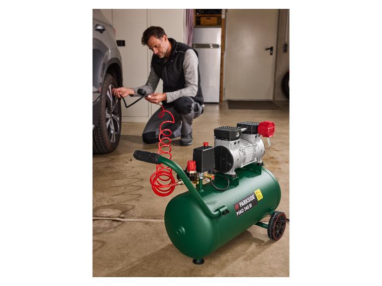 Muž používa vzduchový kompresor Parkside na nafukovanie pneumatiky auta v garáži.