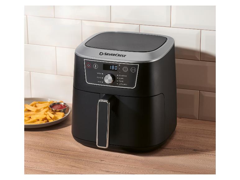 Čierna teplovzdušná fritéza s digitálnym displejom ukazujúcim 180°C, vedľa taniera hranolčekov a kečupu.