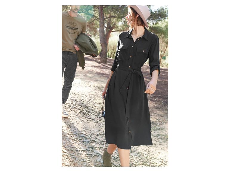 Žena v čiernych šatách s opaskom a klobúkom a muž v tričku s potlačou lietadla.