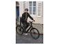 Muž jazdí na čiernom elektrickom bicykli v meste.