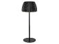 Čierna stojaca lampa s plisovaným tienidlom, vyžarujúca teplú žiaru.