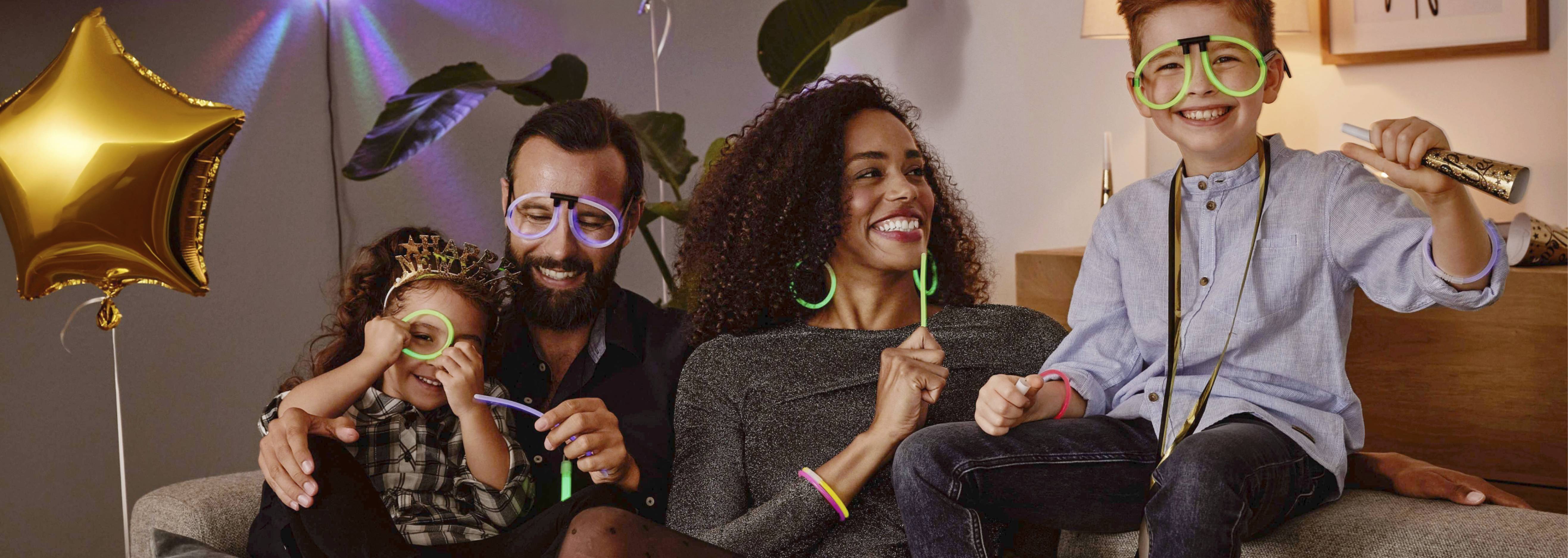Rodina oslavuje Silvestra s neónvými okuliarmi a doplnkami.