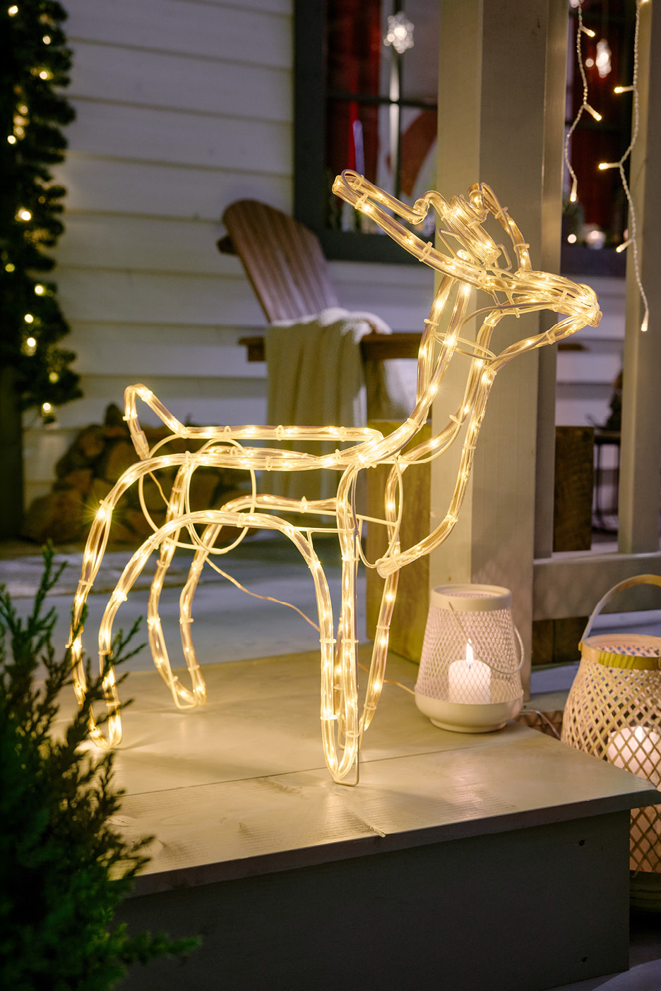 Svetelný vianočný sob na verande s vianočnou výzdobou.