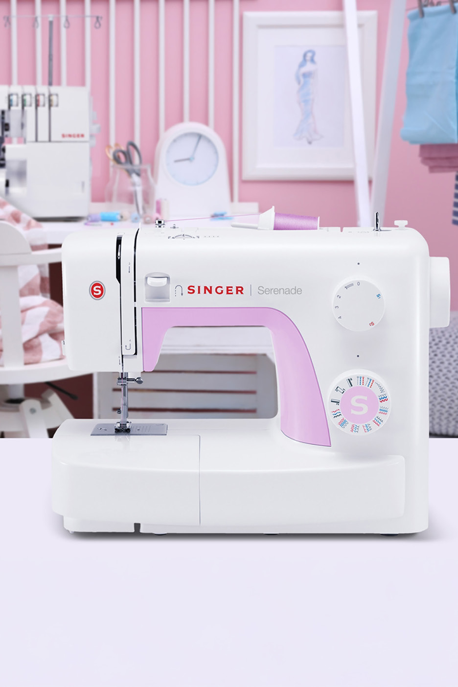 Biely šijací stroj Singer Serenade s ružovými detailmi na stole v ružovej miestnosti.