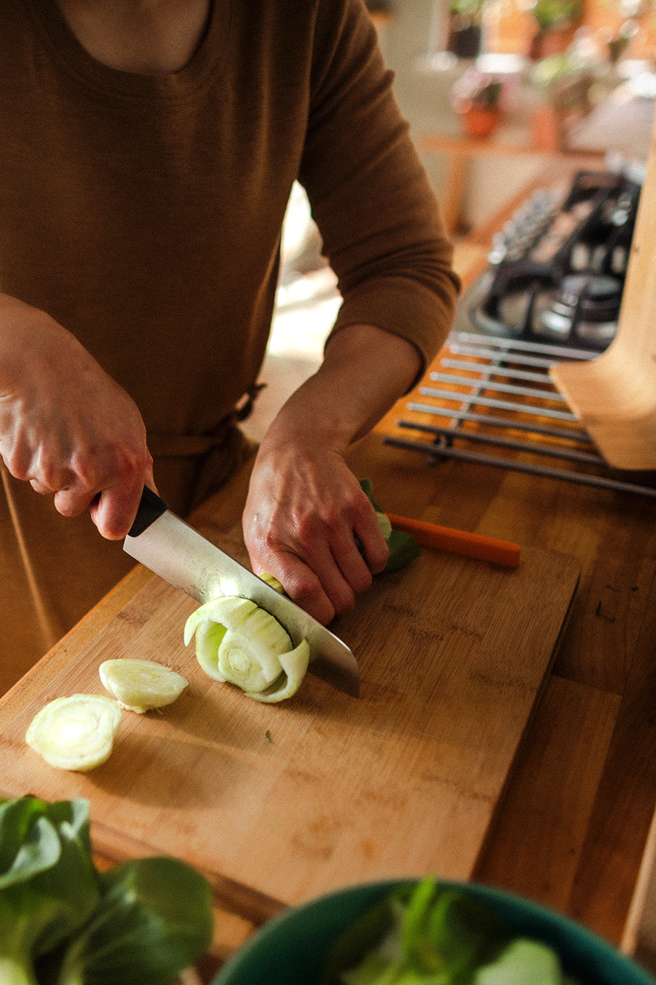 Osoba krája fenikel na drevenej doske v kuchyni.