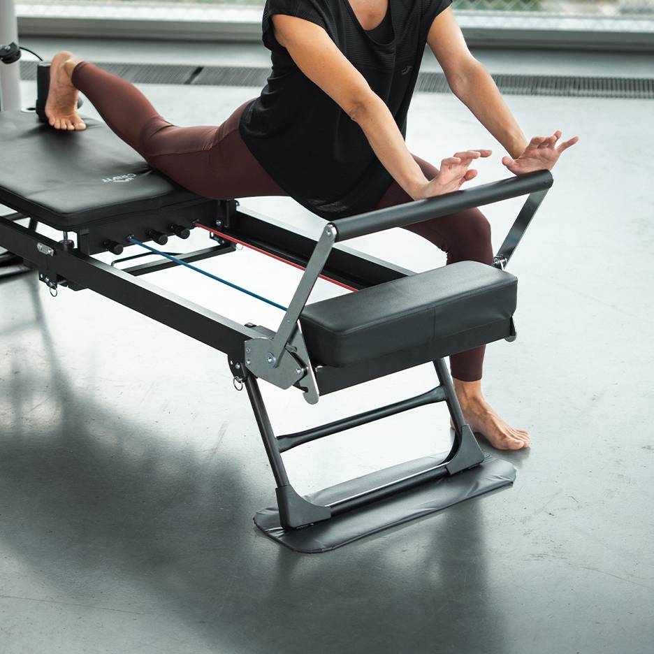 Žena cvičiaca na stroji na Pilates v športovom oblečení