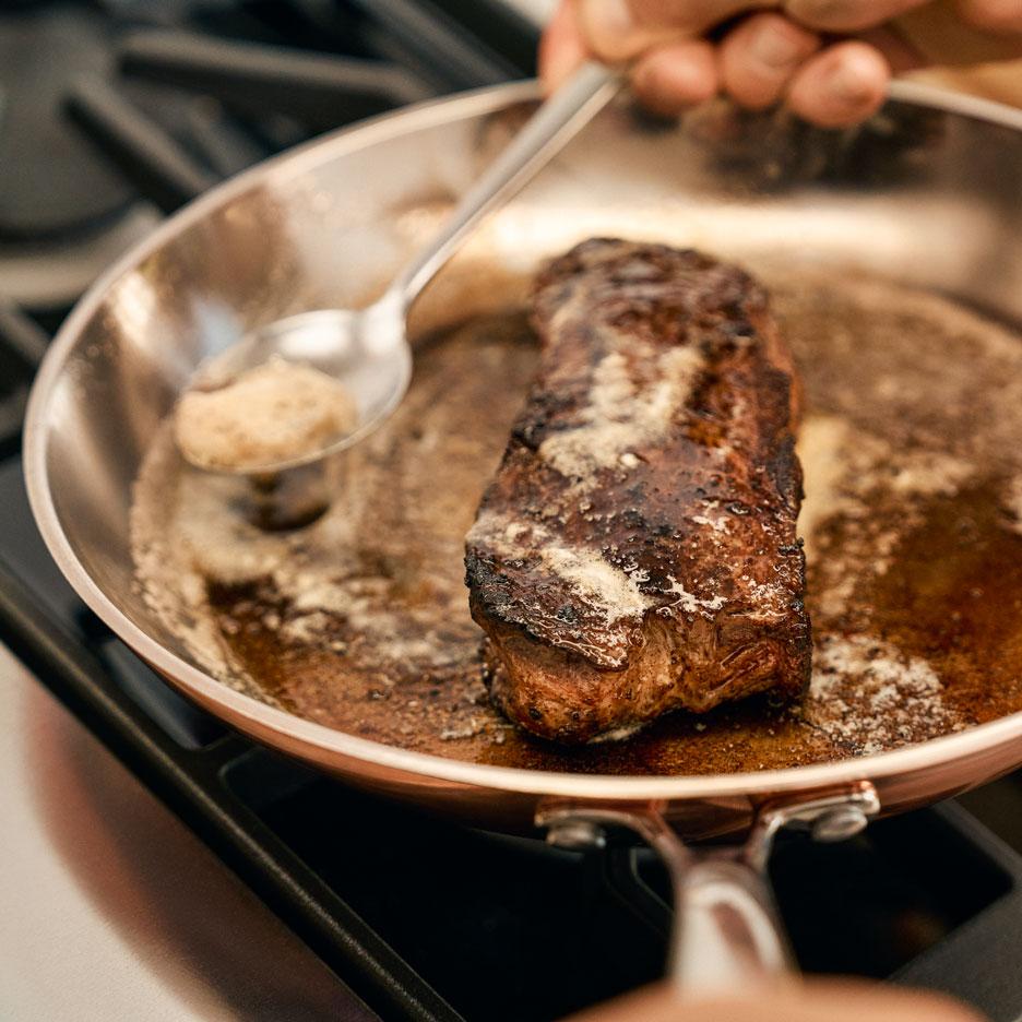 Steak sa pečie na panvici s maslom, ktoré sa naň polieva.