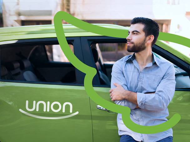 Muž opretý o zelené auto s nápisom „union“ na dverách.