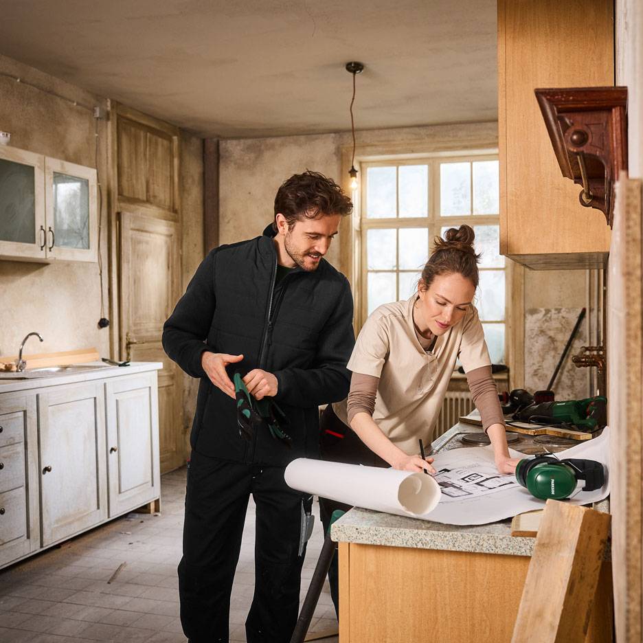 Muž a žena v pracovnom oblečení plánujú renováciu kuchyne.