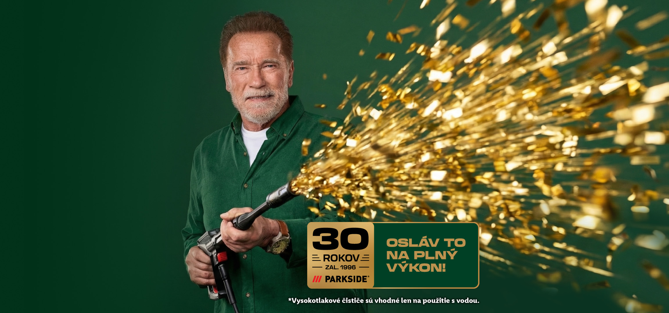 Arnold Schwarzenegger s tlakovým čističom vystreľujúcim zlaté konfety, oslavujúci 30 rokov.