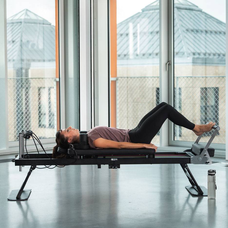 Žena cvičí Pilates na stroji reformer.