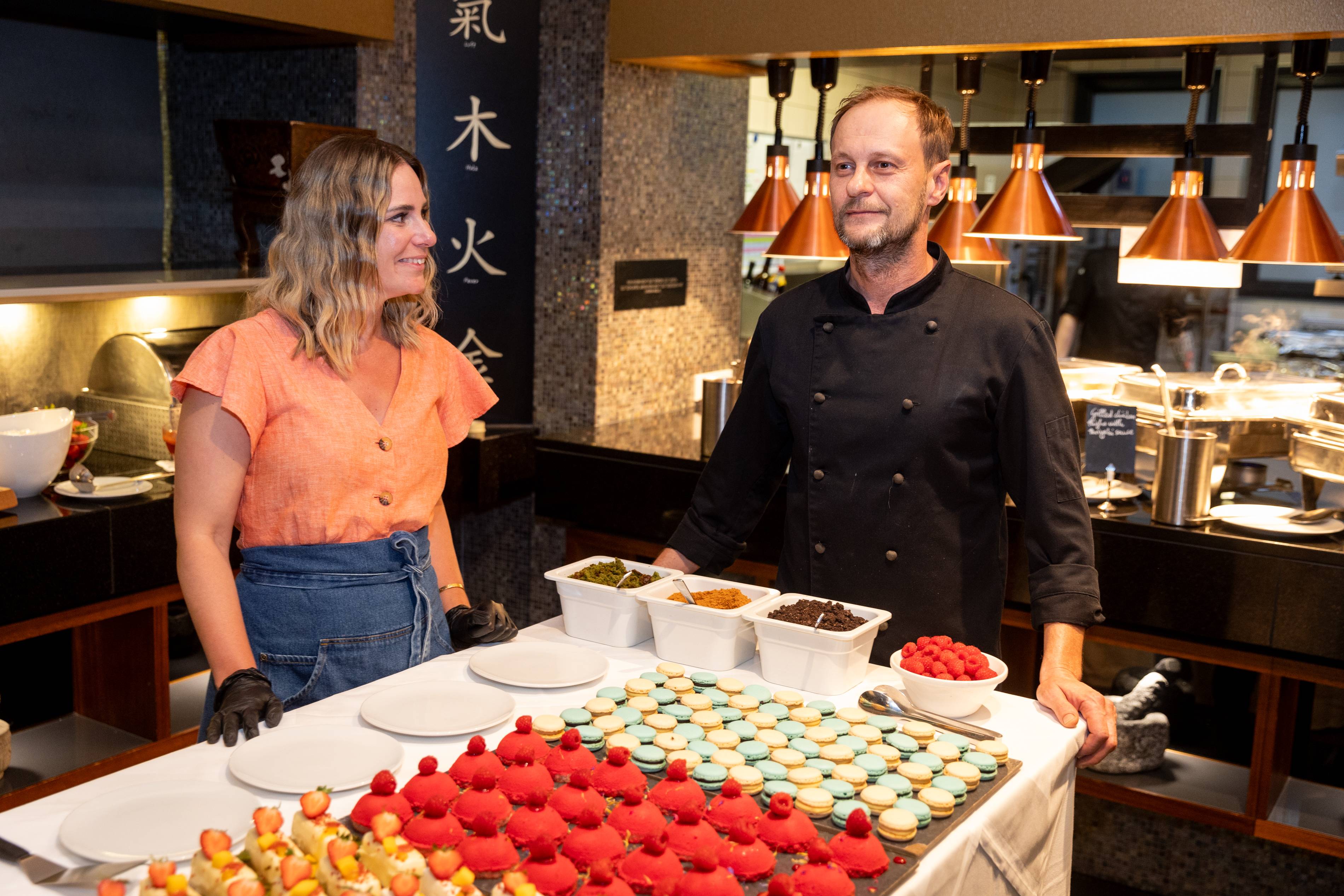 Makrónky, pečivo a kuchár v uniforme pri bufete.