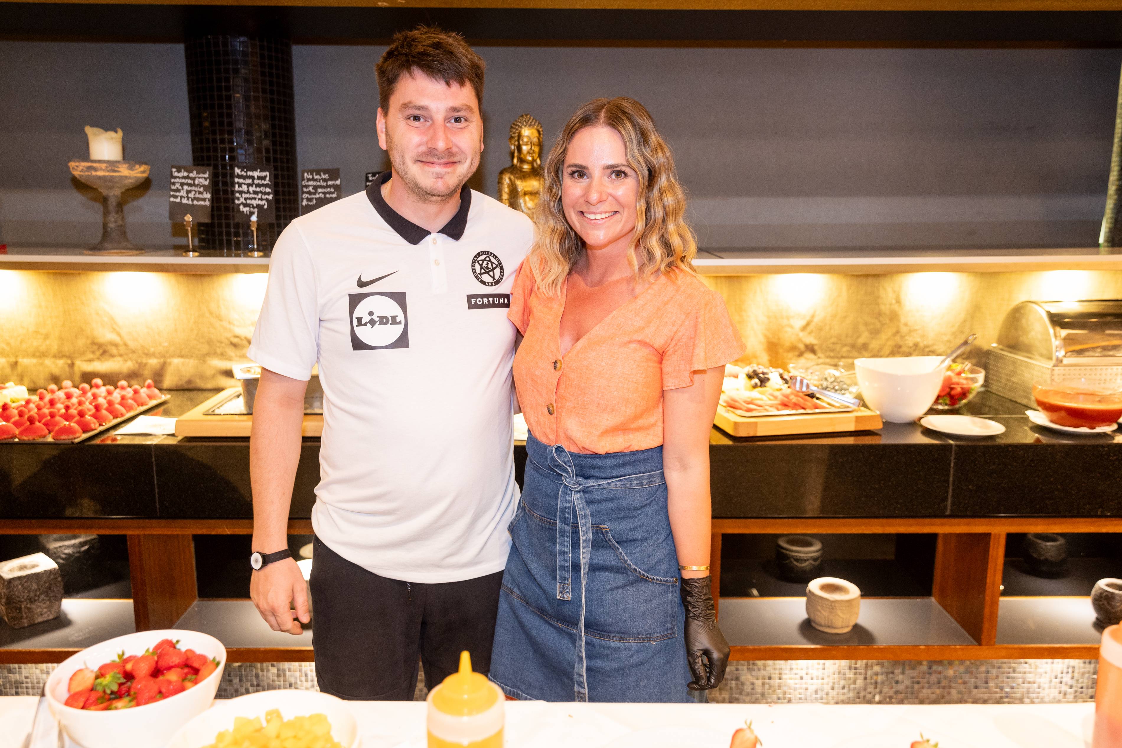 Raňajkový bufet s jahodami a muž v drese Lidl Fortuna.