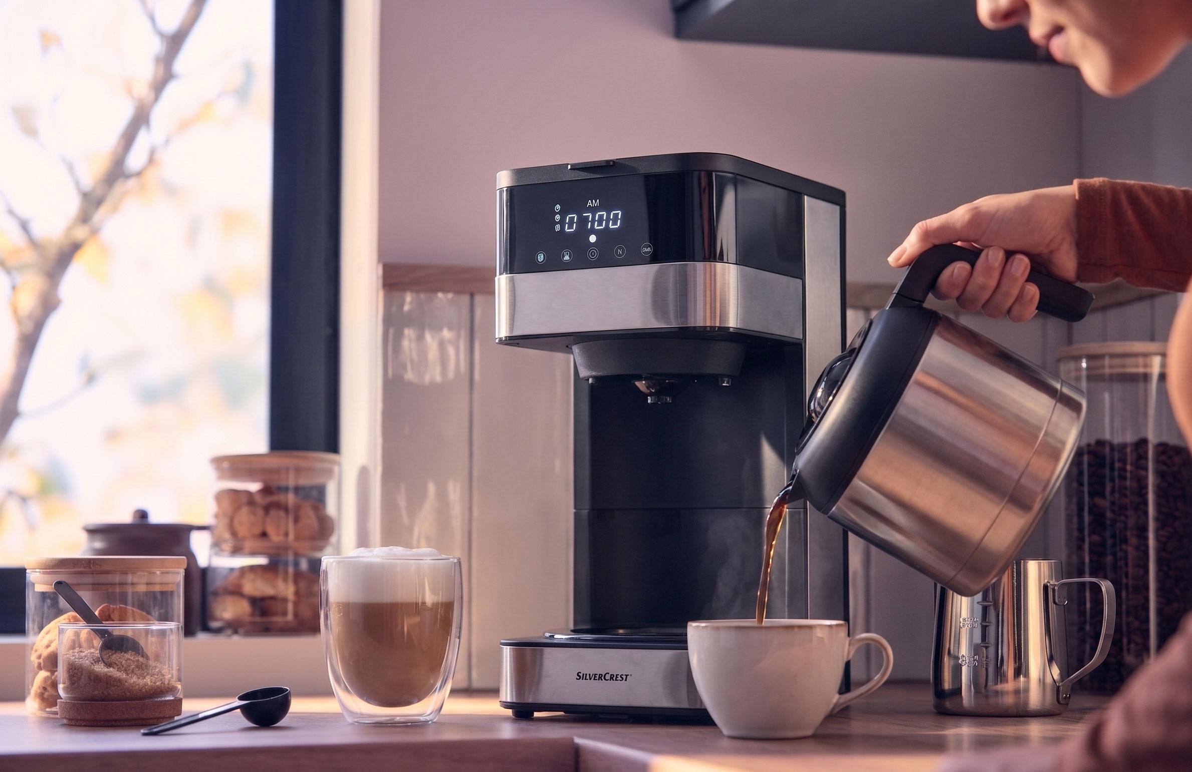 Kávovar nalieva kávu do šálky, s latte a sušienkami na pulte.