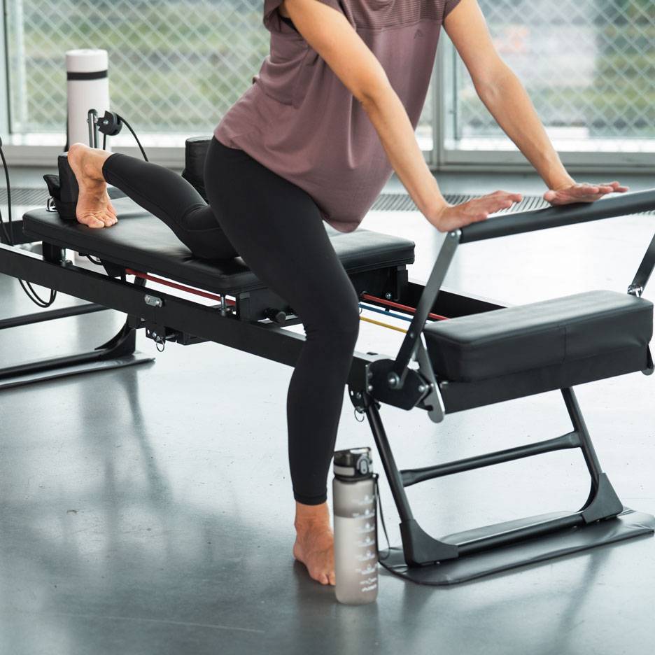 Žena cvičiaca na Pilates stroji s fľašou vody nablízku.