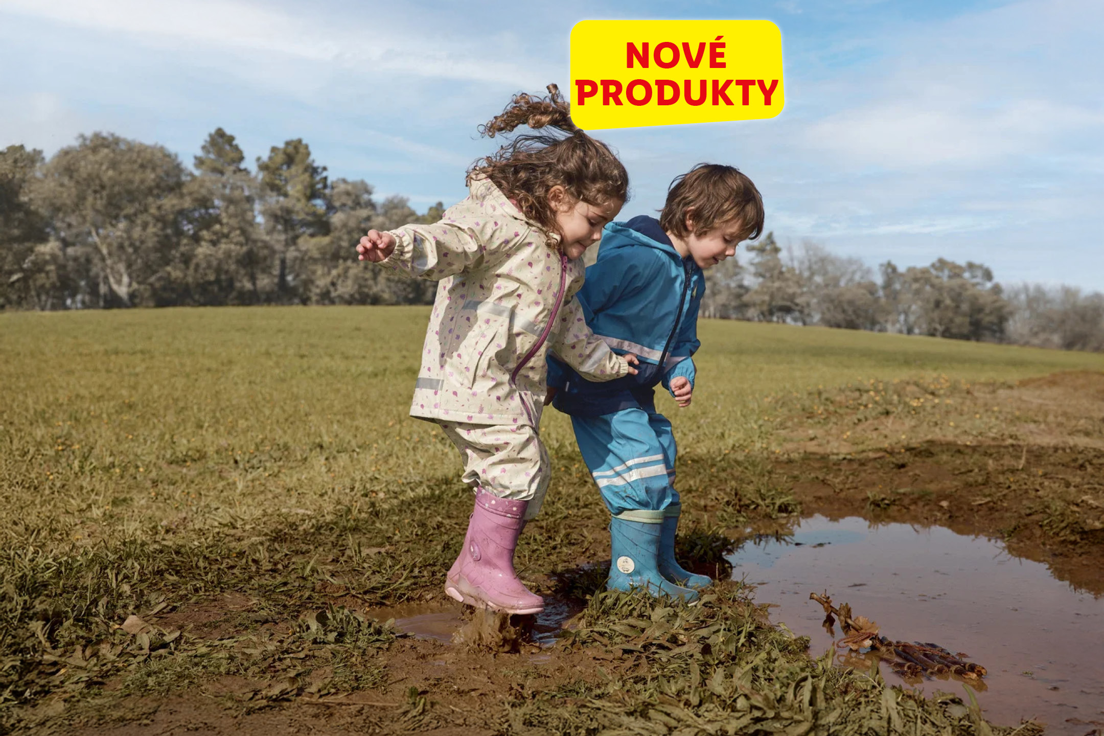 Deti v nepremokavých bundách a čižmách skáču v kaluži. Text: NOVÉ PRODUKTY.