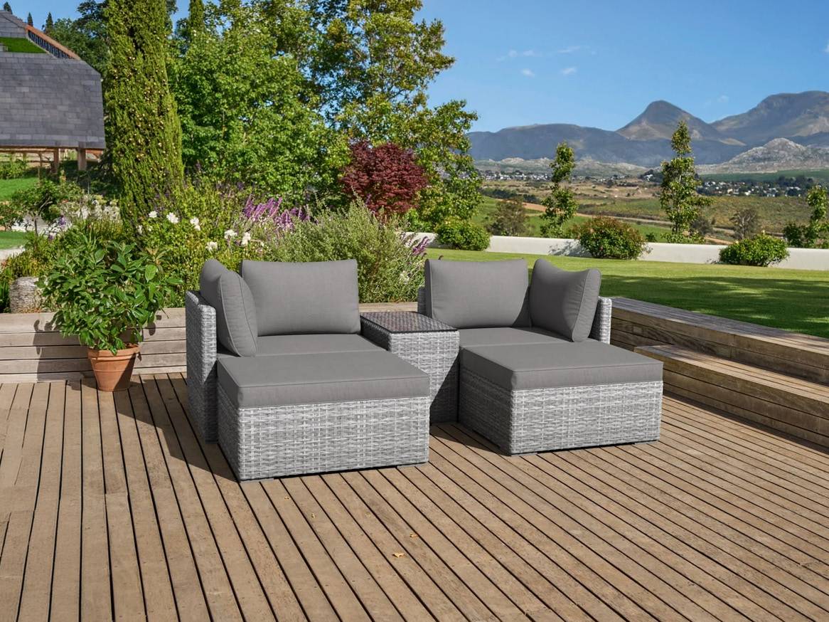 Sivá ratanová záhradná sedacia súprava s vankúšmi na drevenej terase s výhľadom na hory.