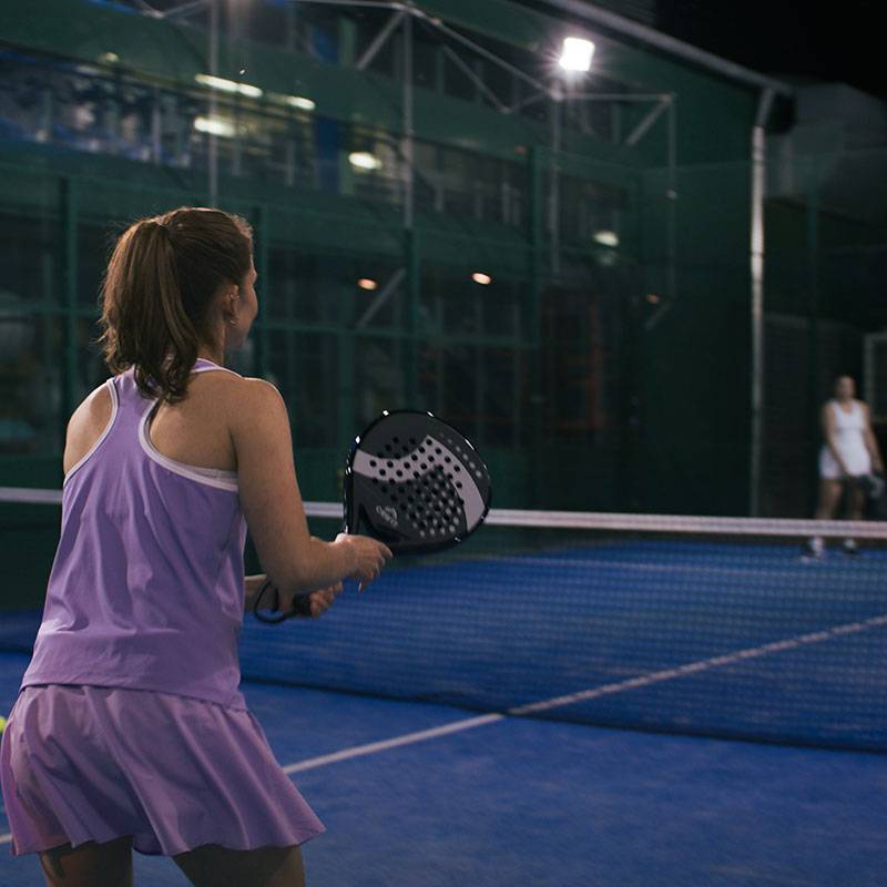 Padel: Žena s raketou na kurte.