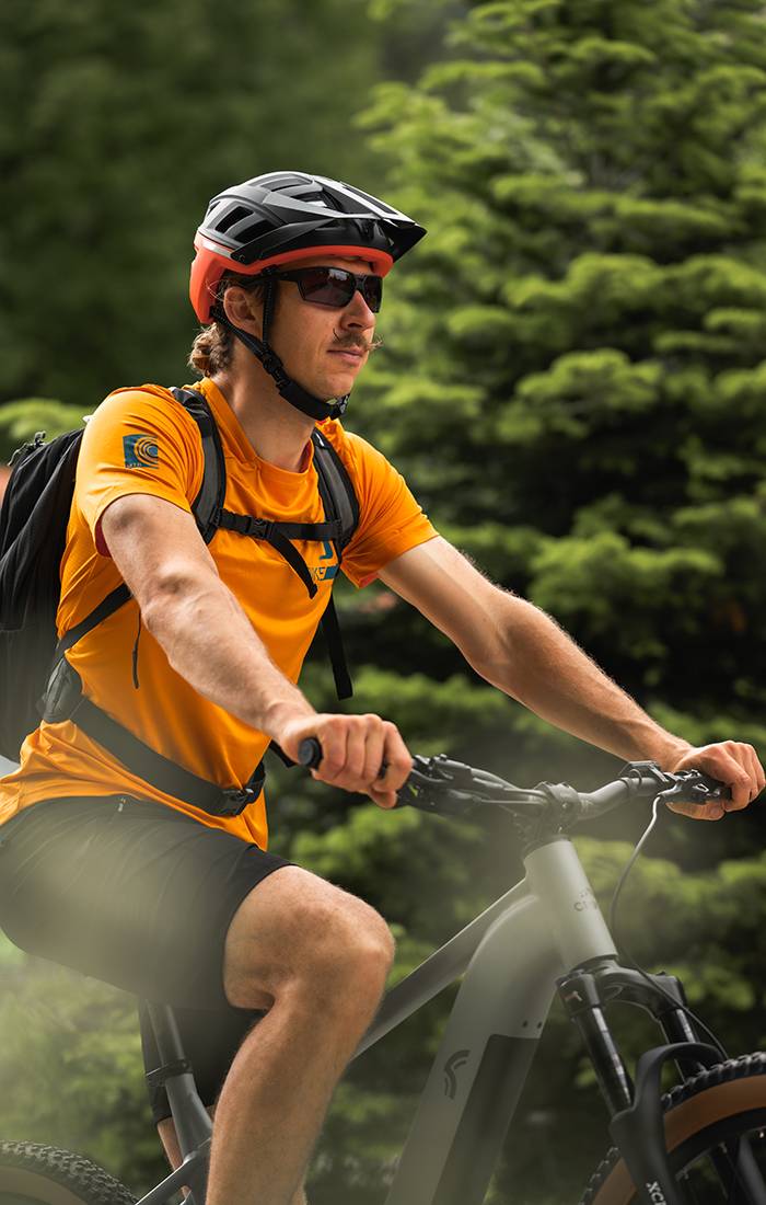 Muž jazdí na horskom bicykli v prilbe a športovom oblečení.