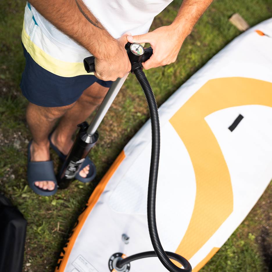 Muž nafukuje nafukovací paddleboard ručnou pumpou.