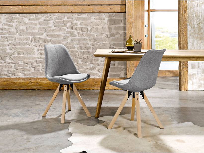 Dve moderné sivé stoličky so svetlými drevenými nohami okolo stola.