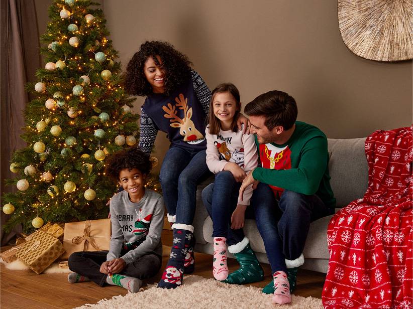 Rodina vo vianočných svetroch a ponožkách pri vianočnom stromčeku.