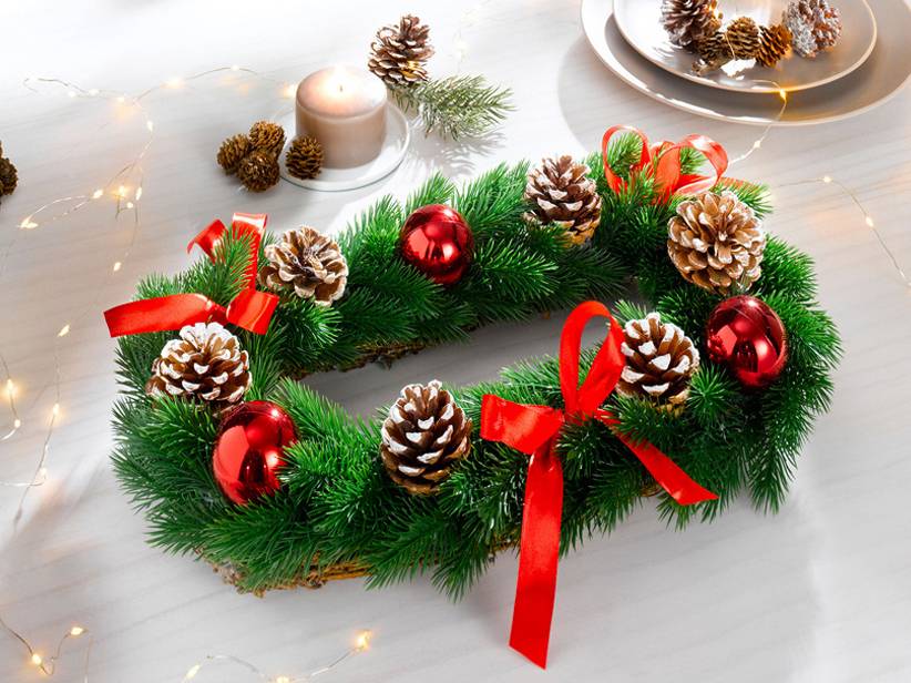Vianočný veniec so šiškami a červenými stuhami.