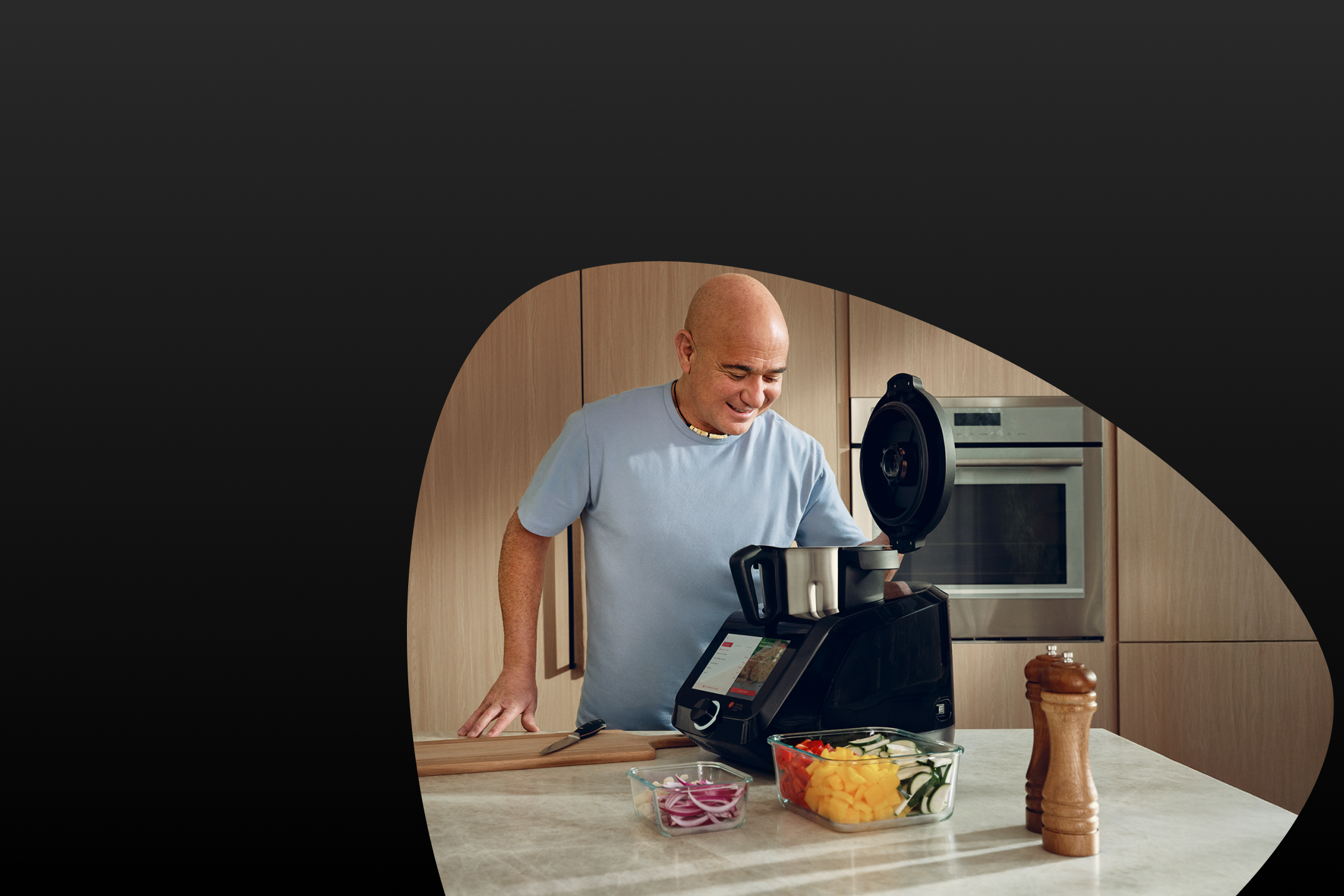 Muž varí s kuchynským robotom Monsieur Cuisine, nakrájaná zelenina vedľa.