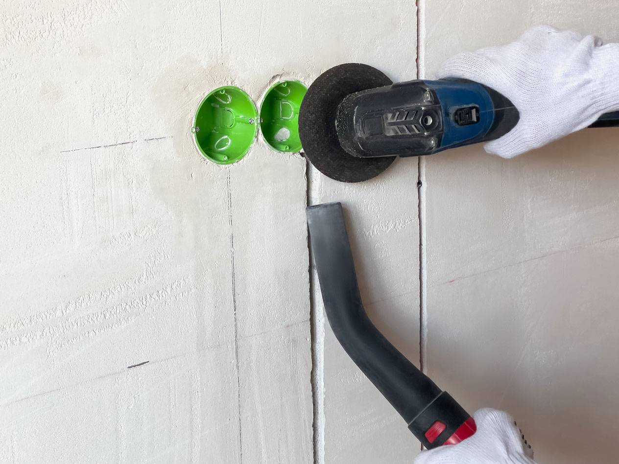 Elektrické náradie reže drážky do steny s vysávačom na prach.
