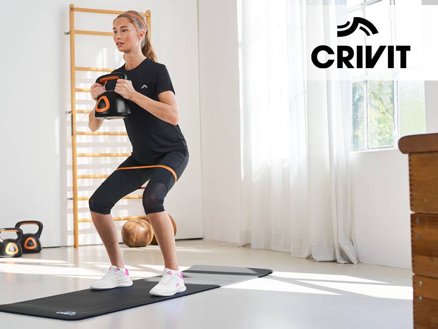 Žena cvičí s kettlebellom a odporovou gumou na podložke na jogu.