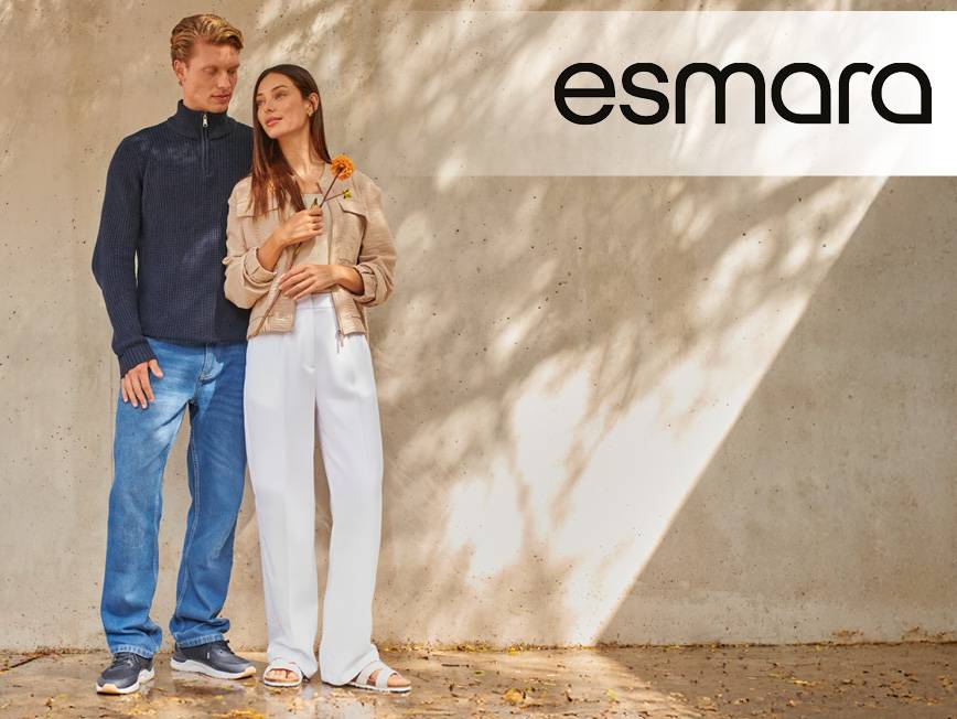 Muž v modrom svetri a džínsoch, žena v béžovej bunde a bielych nohaviciach.