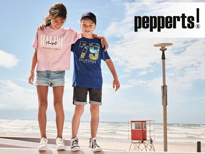 Dievča v ružovom tričku a chlapec v modrom tričku s potlačou na pláži.