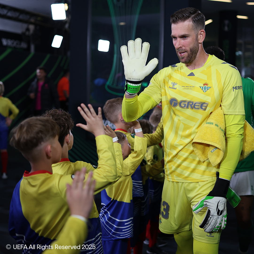 Futbalový brankár v žltom drese Hummel s rukavicami HG Soccer zdraví deti.