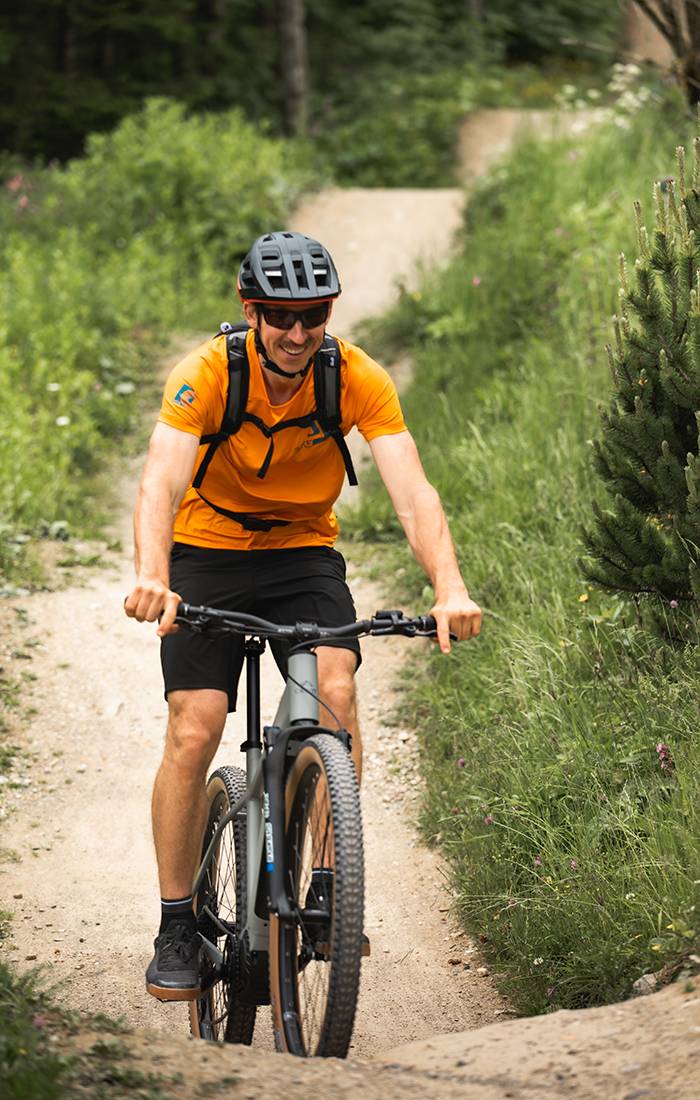 Muž sa usmieva, keď ide na horskom bicykli po ceste.