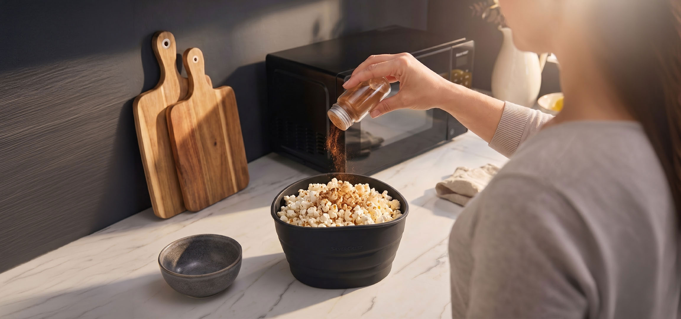 Obrázok bol vygenerovaný pomocou AI: Popcorn v čiernej miske korenený koreninami, vedľa drevených dosiek na krájanie.