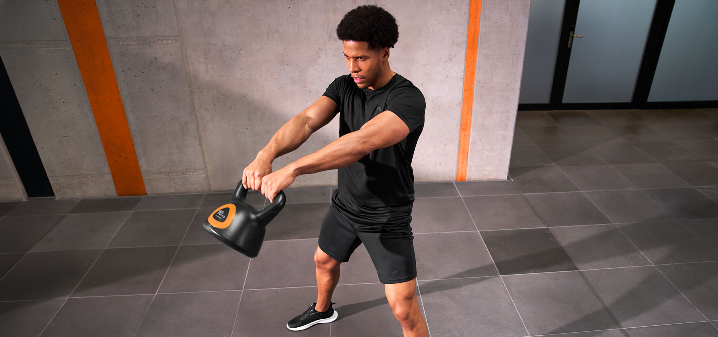 Obrázok bol vygenerovaný pomocou AI: Muž trénuje s čierno-oranžovým kettlebellom.