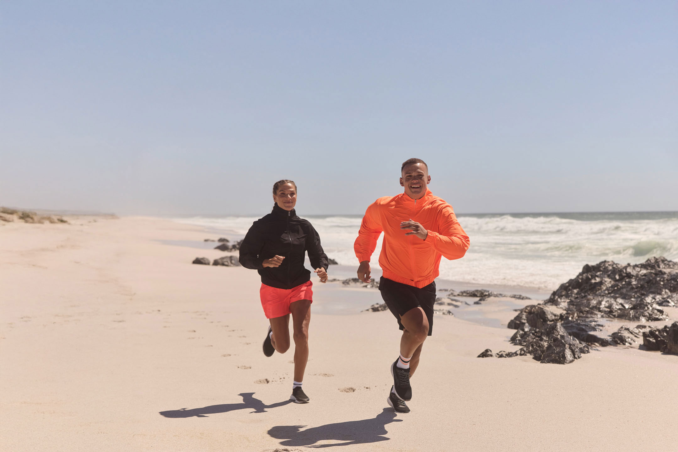 Dve osoby bežiace na pláži.