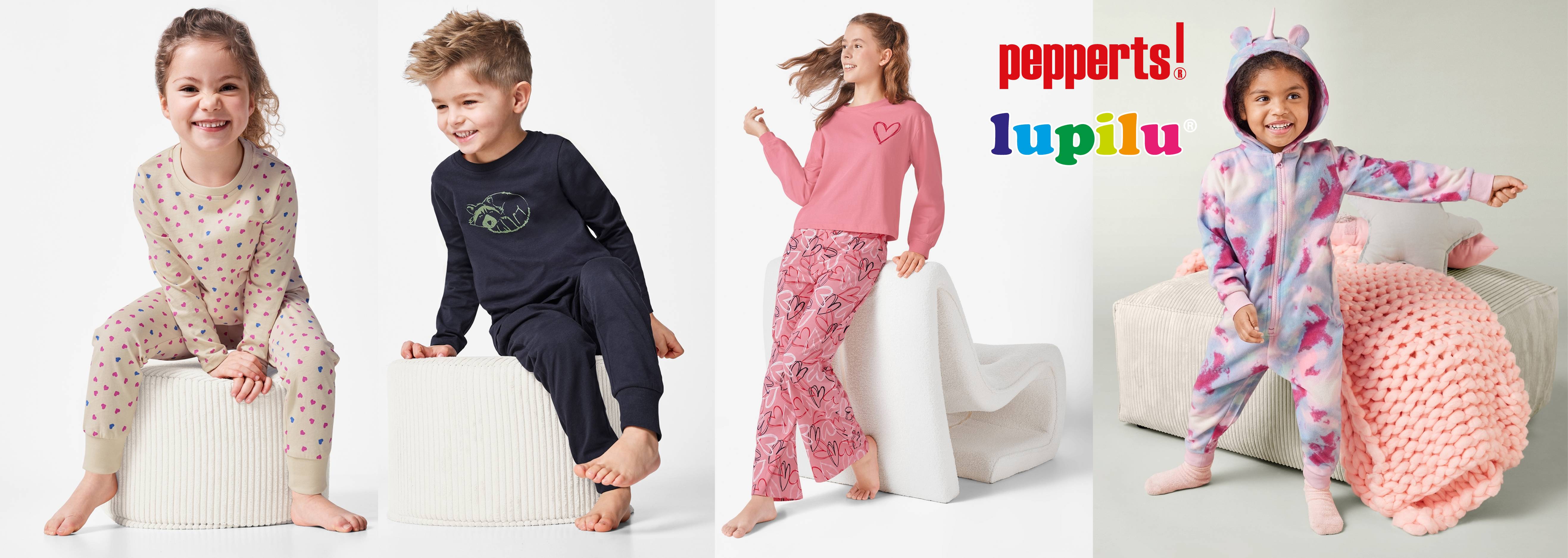 Štyri deti v pyžamách značiek pepperts! a lupilu, vrátane jedného v overale s jednorožcom.