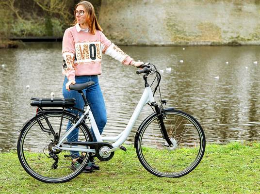 Žena s elektrickým bicyklom pri jazere