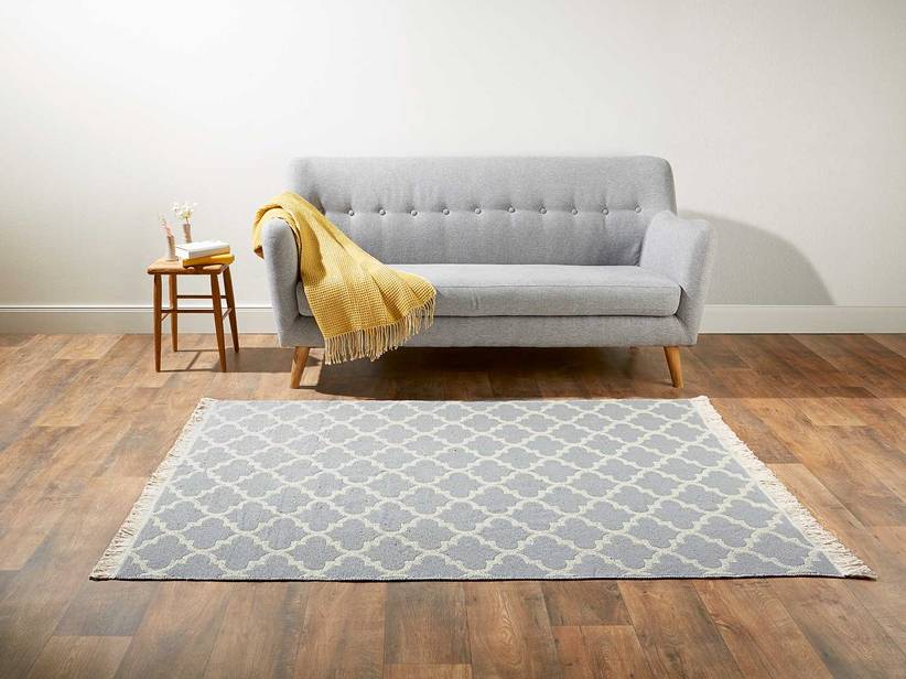 Sivý koberec s geometrickým vzorom a svetlosivá pohovka.
