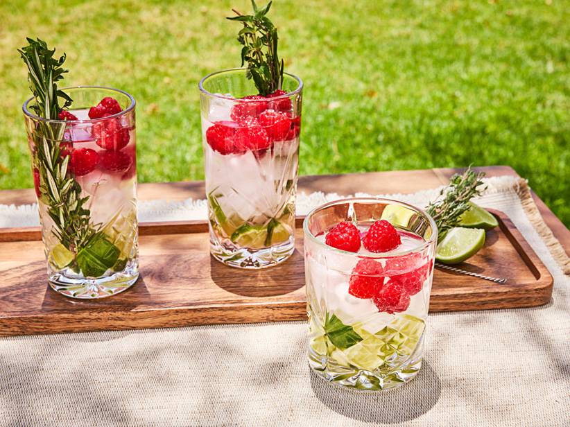 Osvěžujúce nápoje s malinami a bylinkami, podávané vo fasetovaných pohároch.