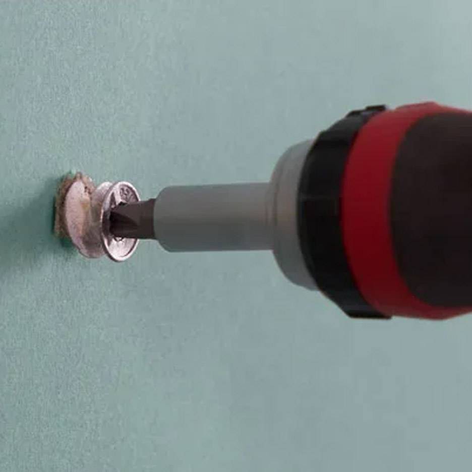 Elektrický skrutkovač s vrtákom vkladá skrutku do steny.
