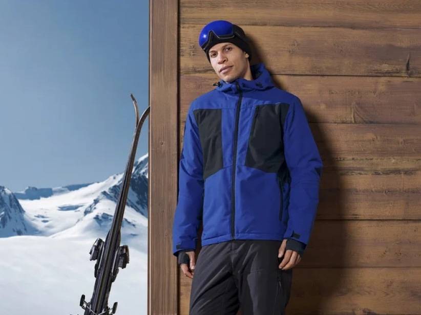 Lyžiarske oblečenie: modrá bunda, lyže a okuliare.