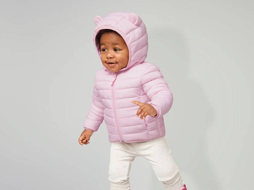 Roztomilé bábätko v ružovej perovej bunde s kapucňou.