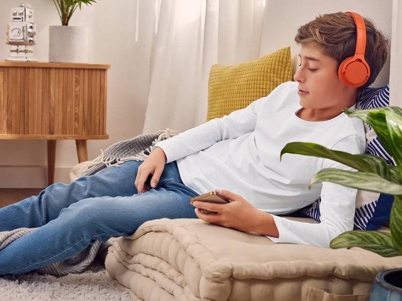 Uvoľnený tínedžer počúva hudbu so slúchadlami Sony a používa smartphone.