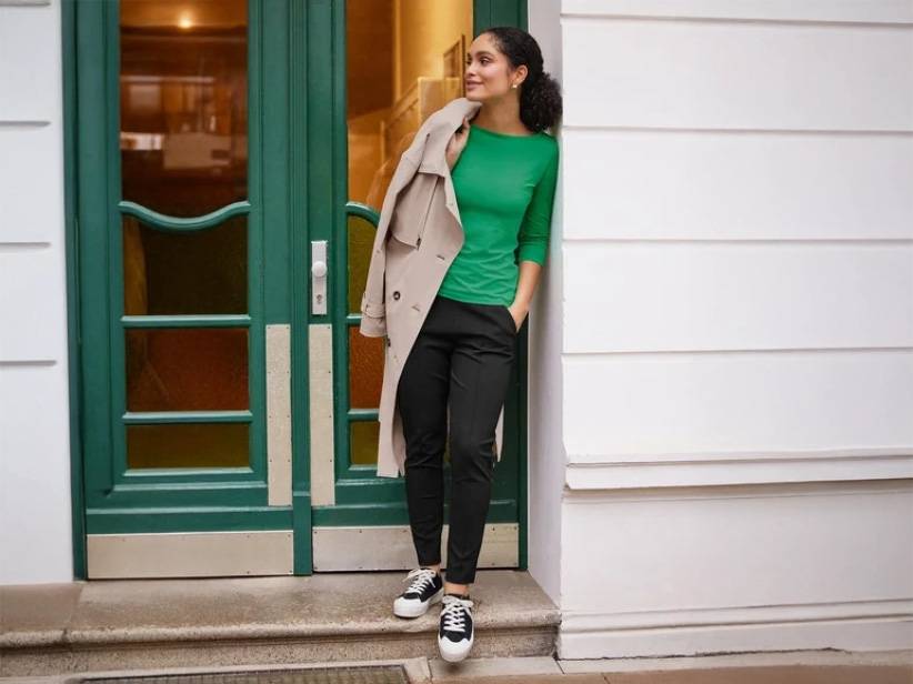 Zelené tričko, čierne nohavice a béžový trenčkot.